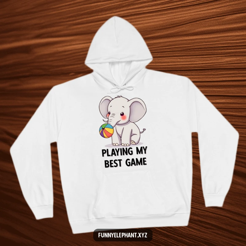 Funny hoodie featuring an elephant energetically bouncing a colorful ball with its trunk, promoting a feeling of joy and playfulness.