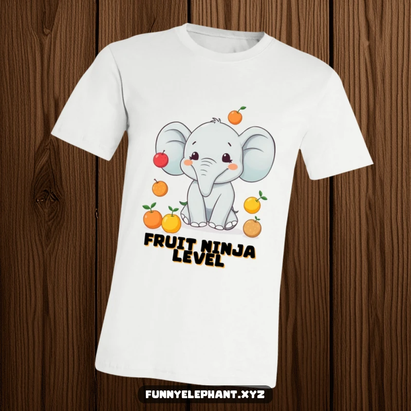 Funny t-shirt depicting an elephant with a wide smile trying to juggle multiple small fruits, showcasing a humorous act of skill.